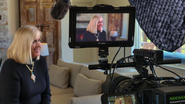 A spokeswoman sits on set ready to talk off camera to an interviewer for a television commercial.